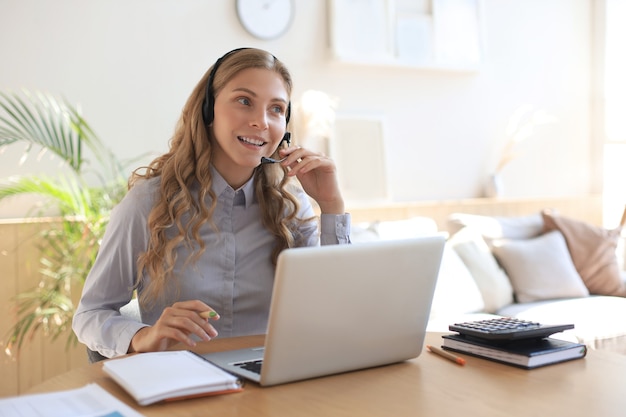 Operador freelance falando com fones de ouvido e clientes de consultoria em casa.