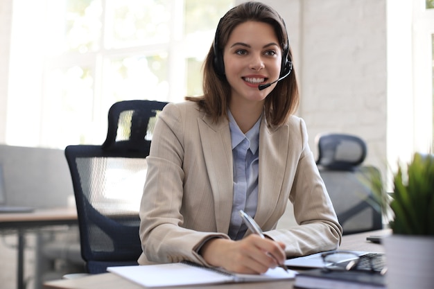 Operador freelance falando com fones de ouvido e consultando clientes do escritório.