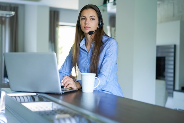 Operador freelancer conversando com fones de ouvido e consultando clientes em home office