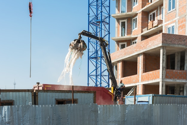 Un operador de grúa carga basura en un camión en un sitio de construcción