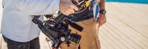 Operador profesional de steadicam utiliza un sistema estabilizador de cámara de 3 ejes en un conjunto de producción comercial BANNER FORMATO LARGO