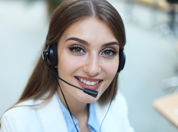 Operador de soporte al cliente femenino con auriculares y sonriendo