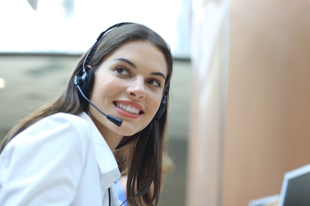 Operador de soporte al cliente femenino con auriculares y sonriendo.