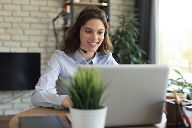 Operador de soporte al cliente femenino con auriculares y sonriendo.