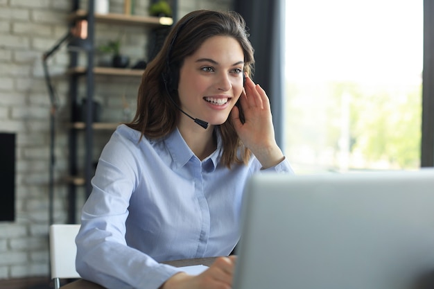 Operador de soporte al cliente femenino con auriculares y sonriendo.