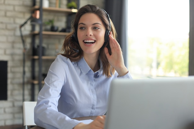 Operador de soporte al cliente femenino con auriculares y sonriendo.