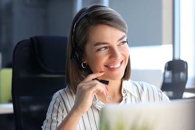 Operador de soporte al cliente femenino con auriculares y sonriendo.