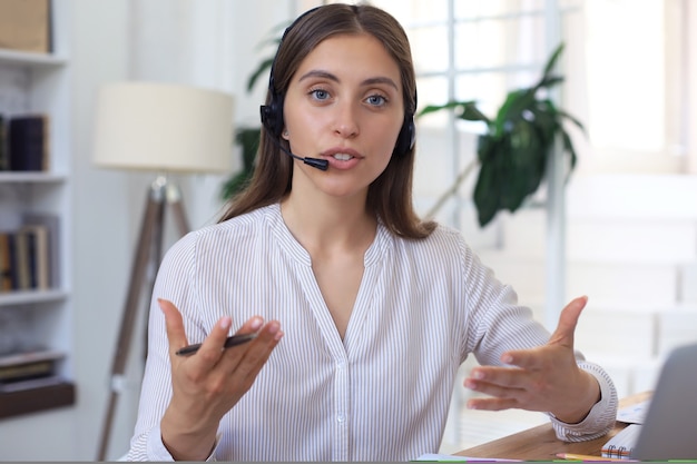 Operador de soporte al cliente femenino con auriculares y sonriendo.