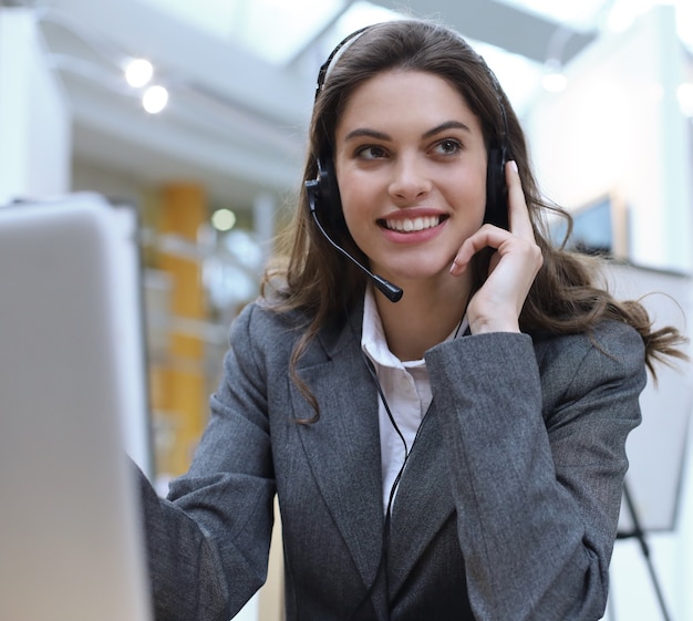 Operador de soporte al cliente femenino con auriculares y sonriendo.