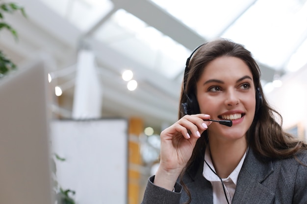 Operador de soporte al cliente femenino con auriculares y sonriendo.