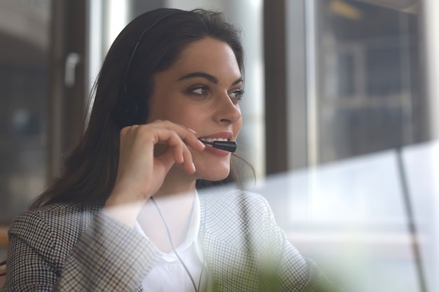 Operador de soporte al cliente de mujer con auriculares y sonriendo.