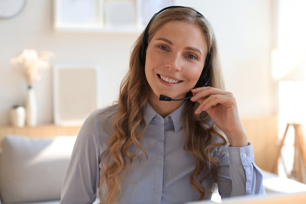 Operador de soporte al cliente de mujer con auriculares y sonriendo.