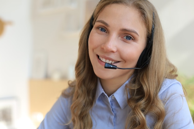 Operador de soporte al cliente de mujer con auriculares y sonriendo.