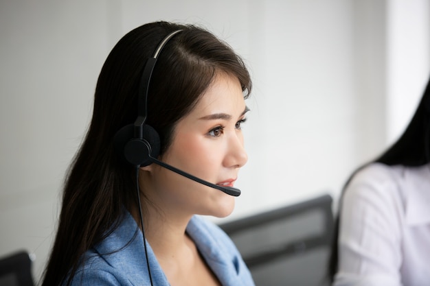 Operador de soporte técnico con auriculares trabajando en computadora portátil y computadora