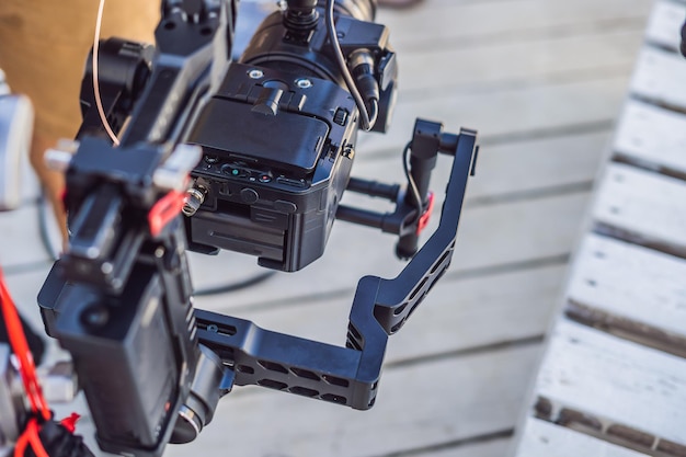 Foto el operador de steadicam y su asistente preparan la cámara y el estabilizador de 3 ejes para una filmación comercial