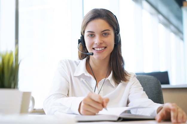 Operadora de suporte ao cliente feminino com fone de ouvido e sorrindo.