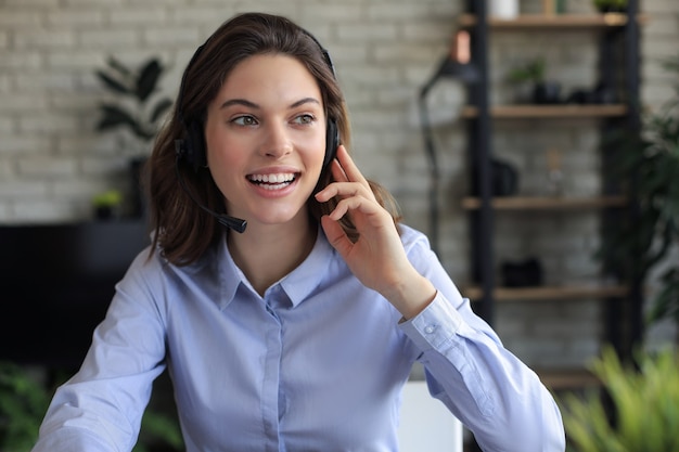 Foto operadora de suporte ao cliente feminino com fone de ouvido e sorrindo.