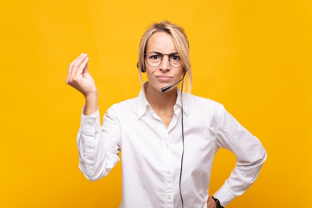 Operadora de telemarketing jovem fazendo capice ou gesto de dinheiro, dizendo para você pagar suas dívidas!