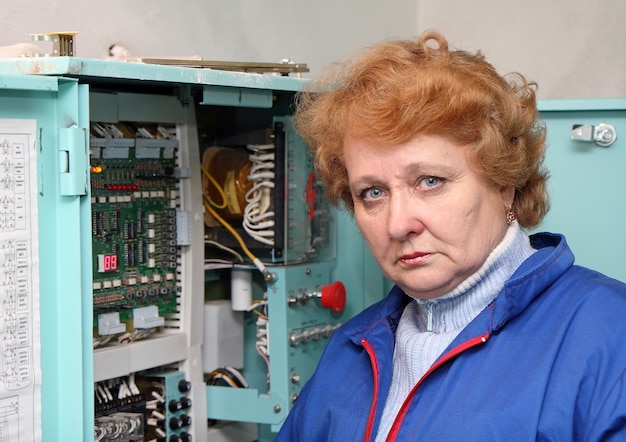 Operadora engenheira na sala de máquinas (elevador) perto do gabinete eletrônico.