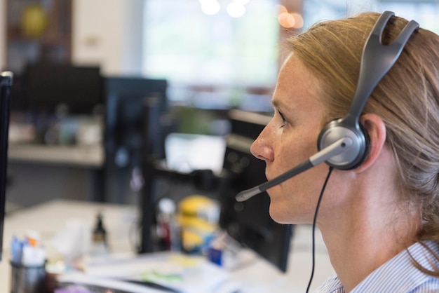 Foto operadora telefónica de atención al cliente femenina con auriculares en el lugar de trabajo