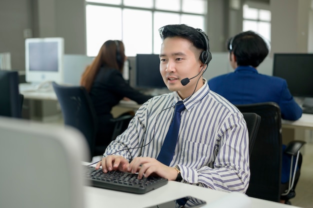 Operadores asiáticos estão usando fones de ouvido no local de trabalho.