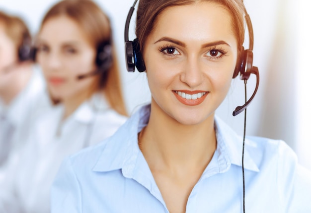 Operadores de centros de llamadas. Concéntrese en una hermosa mujer de negocios usando auriculares en una oficina soleada.