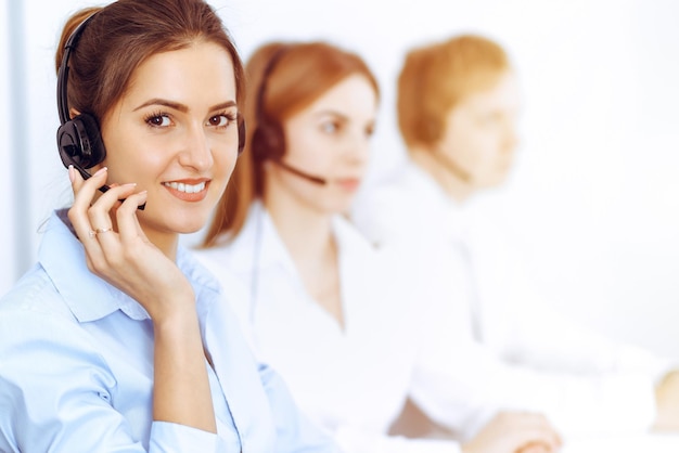 Operadores de call center. concentre-se na bela mulher de negócios usando fone de ouvido no escritório ensolarado.