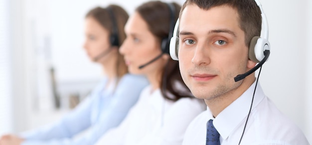 Operadores de call center. Concentre-se no empresário no fone de ouvido enquanto consulta os clientes.