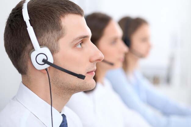 Operadores de call center. Concentre-se no empresário no fone de ouvido enquanto consulta os clientes.