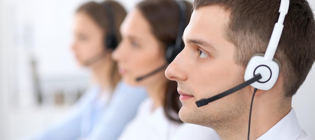 Operadores de call center. Concentre-se no empresário no fone de ouvido enquanto consulta os clientes.