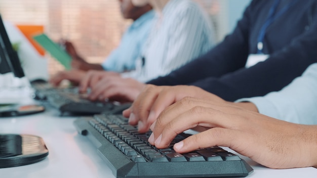 Operadores manos escribiendo en el teclado en la oficina moderna.