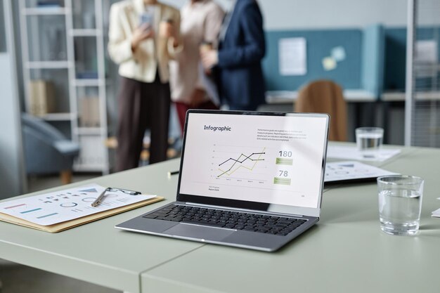 Operando una computadora portátil en la mesa de la oficina con un informe de negocios en la pantalla