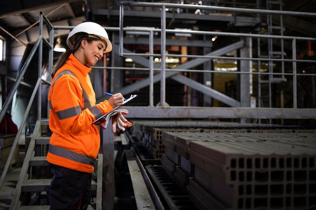 Operária feminina verificando a qualidade dos tijolos de construção para a indústria da construção