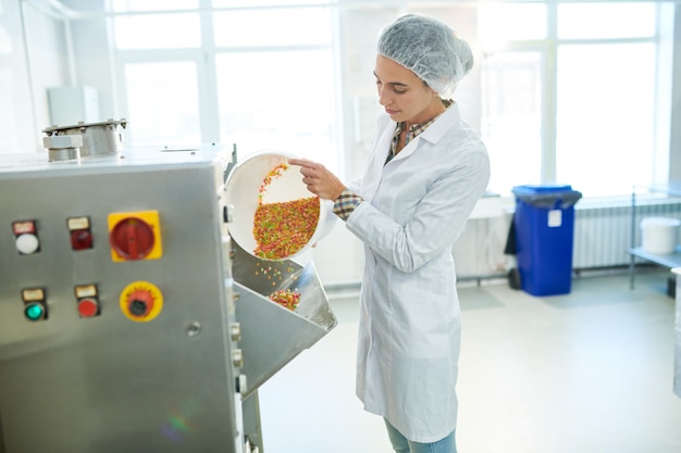 Foto operário de confeitaria derramando arco-íris polvilha na máquina