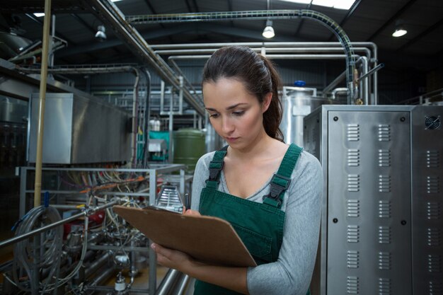 Foto operário feminino, mantendo o registro na área de transferência na fábrica