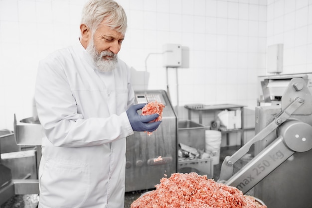 Operário observando a carne, estando o equipamento próximo.