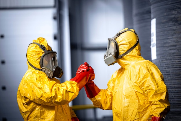 Operários em trajes de proteção química e máscaras de gás cumprimentando uns aos outros