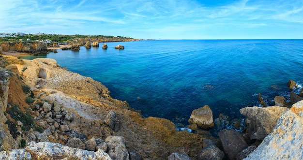 Opinião da costa rochosa do atlântico do verão da noite (albufeira, algarve, portugal). as pessoas estão irreconhecíveis. panorama de pontos de quatro tiros.