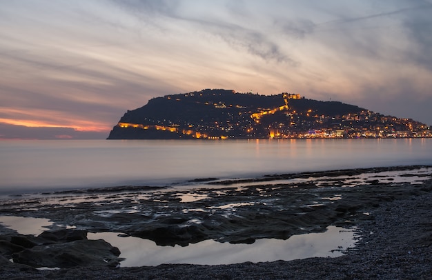 Opinião do por do sol do porto, do mar e da fortaleza em alanya, turquia.