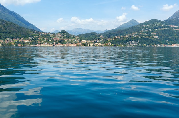 Opinião do verão do Lago Como (Itália) e a cidade de Menaggio na costa.