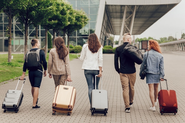 Opinião traseira jovens positivos com a bagagem ao ar livre.