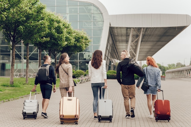 Opinião traseira jovens positivos com a bagagem ao ar livre.