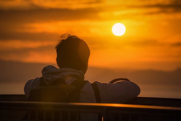 Foto opinião traseira o homem do viajante que olha o mar no por do sol em shizuoka, japão.