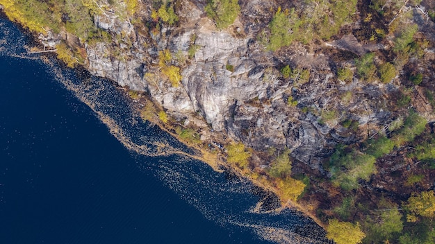 Opinión del abejón aéreo sobre el lago y los acantilados de Yastrebinoe. Hermoso paisaje de temporada con un lago o agua de río y alerces. Rusia, Karelia.