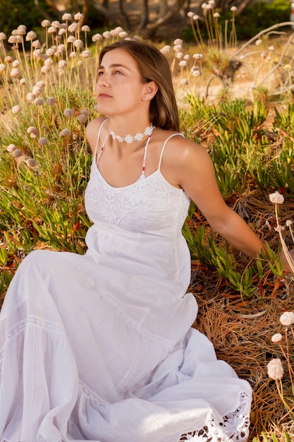 Opinión una chica joven hermosa con un vestido blanco largo en el bosque.