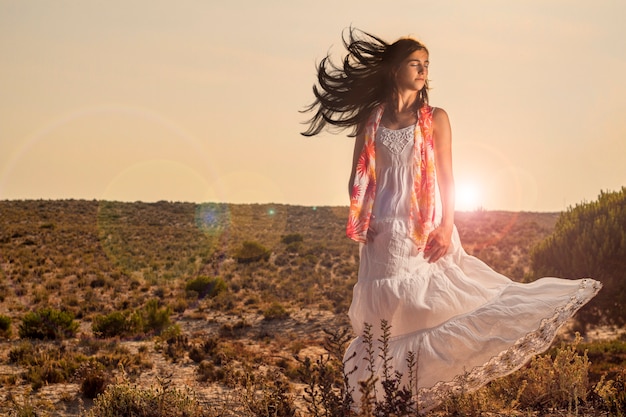 Opinión una chica joven hermosa con un vestido blanco largo en el bosque.