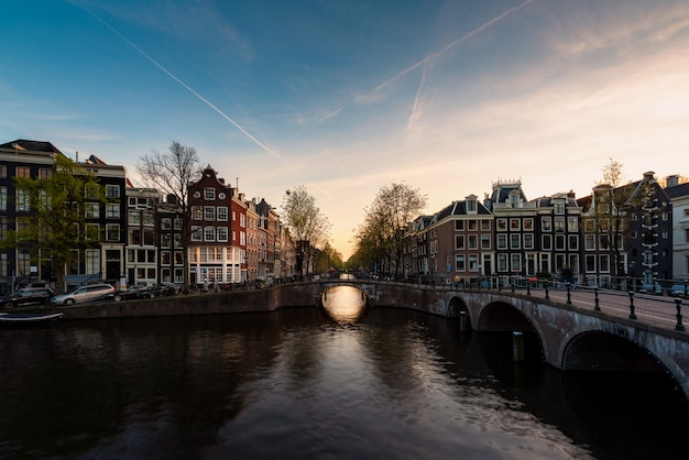 Opinión de la ciudad de Amsterdam, los Países Bajos con el río de Amstel durante puesta del sol.