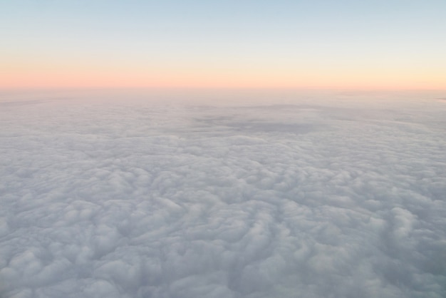 Opinión del iluminador del aeroplano sobre las nubes mullidas y el cielo de la salida del sol. Vista de las nubes desde el iluminador del avión