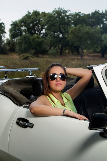 Opinión una mujer hermosa que presenta en un coche convertible blanco.