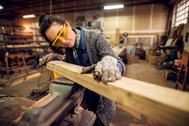 Opinión del retrato del trabajador carpintero profesional de mediana edad profesional trabajador feliz feliz que mira y que elige la madera en el taller o el garaje.